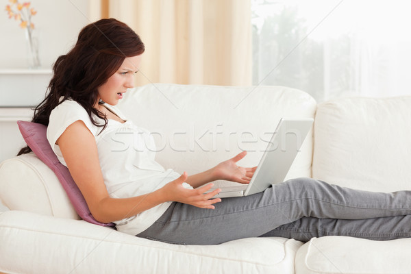 Annoyed woman with a laptop in her livingroom Stock photo © wavebreak_media