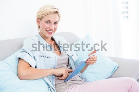 Woman pointing a remote at the camera with a knowing smile in the living room Stock photo © wavebreak_media