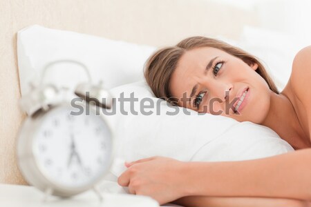 Unhappy woman awaken by an alarmclock in her bedroom Stock photo © wavebreak_media