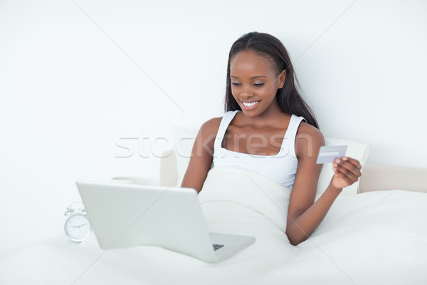 Stock photo: Young woman purchasing online in her bedroom