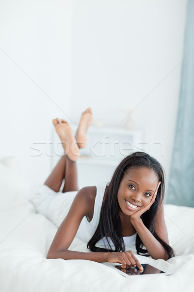 Portrait of a woman lying on her bed with a tablet computer while looking at the camera Stock photo © wavebreak_media