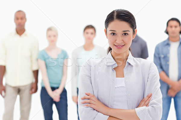 Close-up of a girl crossing her arms with people behind against white background Stock photo © wavebreak_media