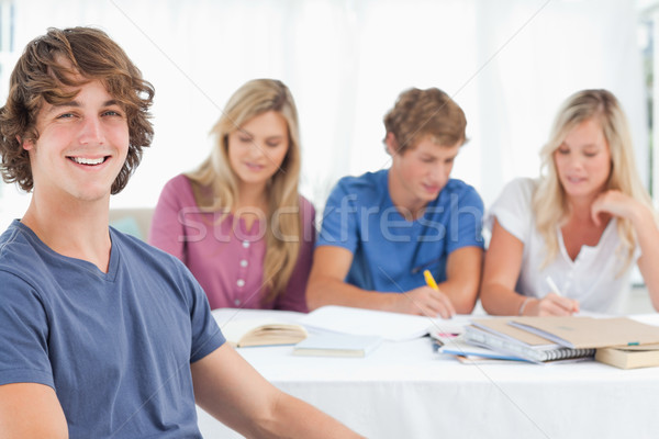 Stock photo: A close up shot of a man sitting in front of his friends as he looks at the camera