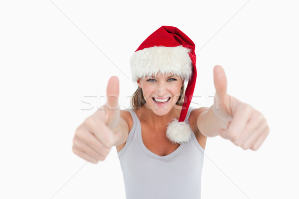 Woman with the thumbs up and a Christmas hat against a white background Stock photo © wavebreak_media