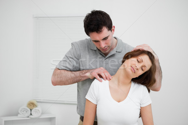 Serious osteopath palpating the trapezius of a woman in a room Stock photo © wavebreak_media