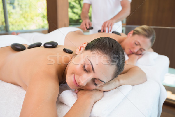 Calm friends lying on massage tables with hot stones on their ba Stock photo © wavebreak_media