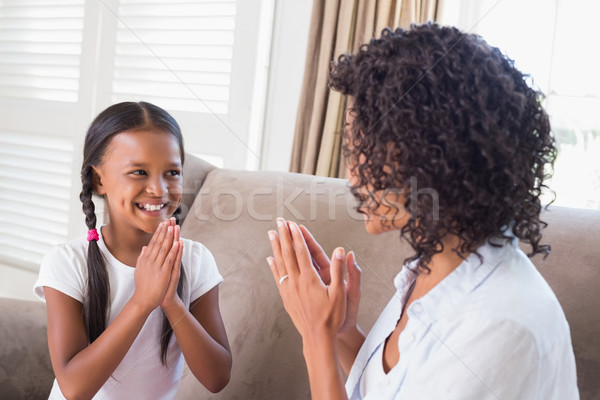 Pretty mother playing clapping game with daughter on couch Stock photo © wavebreak_media