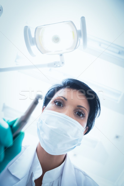 Female dentist in surgical mask holding dental drill Stock photo © wavebreak_media