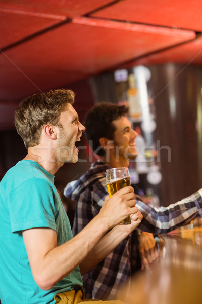 Happy friends sitting and drinking beer Stock photo © wavebreak_media