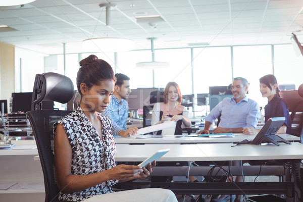 Young businesswoman using digital tablet while colleagues discussing in office Stock photo © wavebreak_media