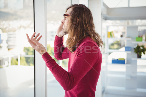 Hipster talking on cellphone standing by window Stock photo © wavebreak_media