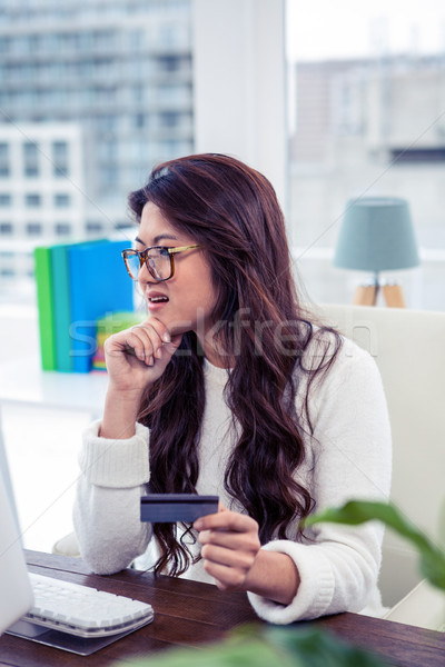 Asian woman with hand on chin holding credit card Stock photo © wavebreak_media