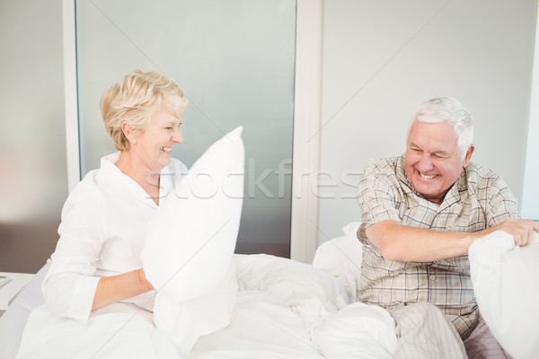 Foto stock: Pareja · de · ancianos · pelea · de · almohadas · cama · feliz · casa · amor