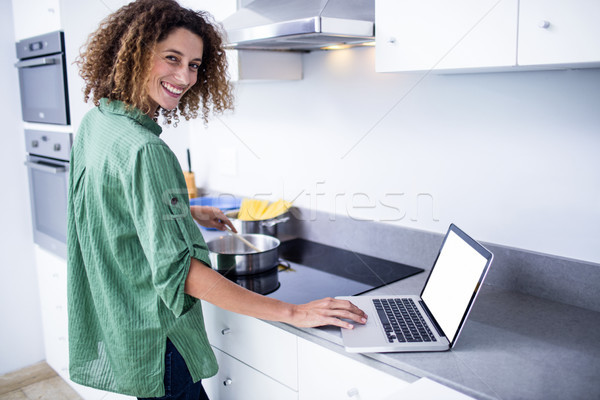 Portrait of woman working on laptop while cooking Stock photo © wavebreak_media