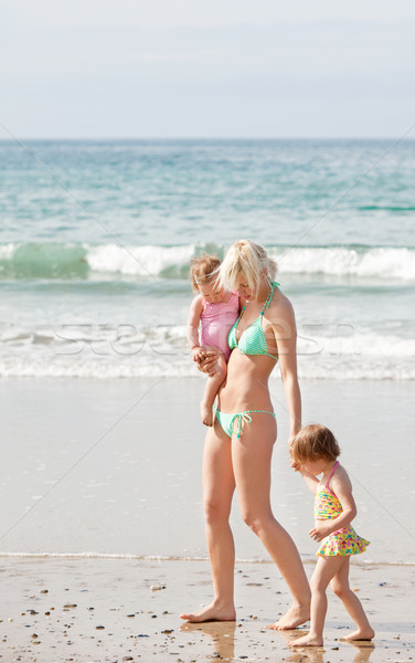 Stock photo: A young mother walking at the beach with her children