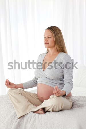 Vue de côté femme enceinte yoga lit maison sourire [[stock_photo]] © wavebreak_media