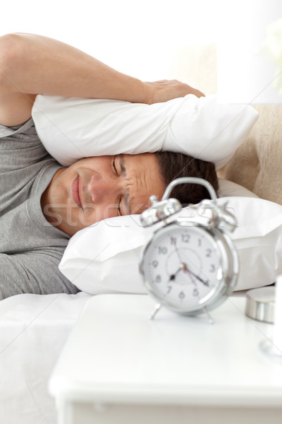 Displeased Man Putting His Head Under The Pillow While His Alarm