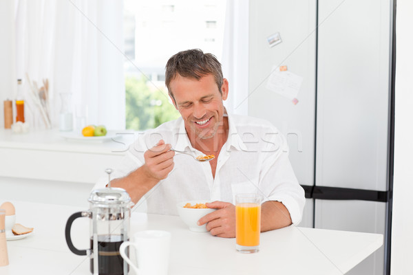 Сток-фото: красивый · мужчина · завтрак · кухне · домой · улыбка · оранжевый