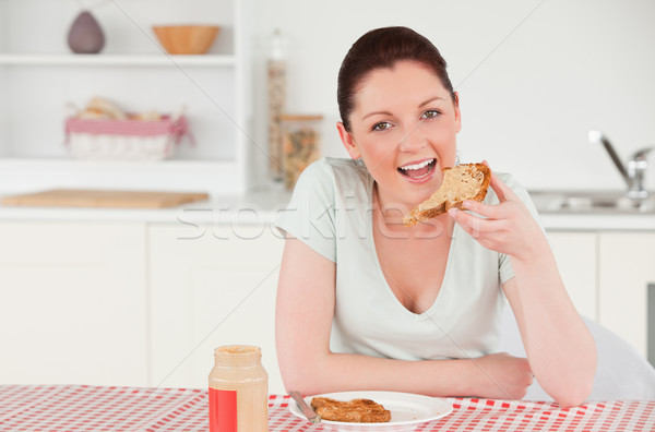 Good looking woman posing while eating a slice of bread in her kitchen Stock photo © wavebreak_media