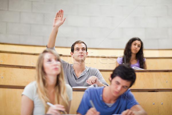 Student raising his hand while his classmates are taking notes in an amphithater Stock photo © wavebreak_media