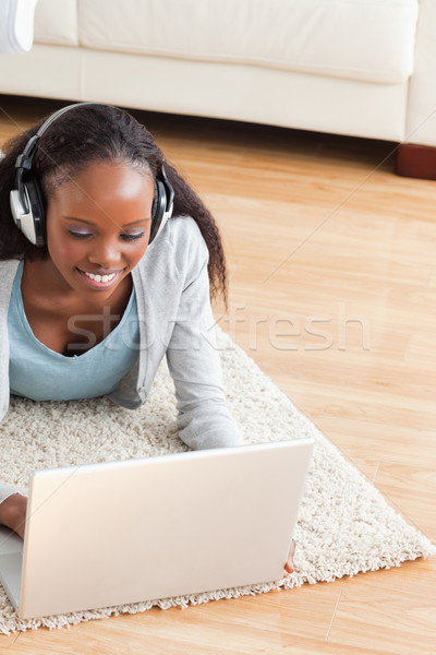 Close up of smiling woman lying on floor with laptop listening to music Stock photo © wavebreak_media