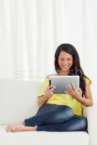 Beautiful smiling Latino looking a touch pad on a sofa Stock photo © wavebreak_media