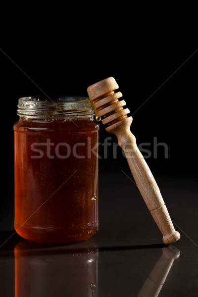 Honey jar and honey dipper against a black background Stock photo © wavebreak_media