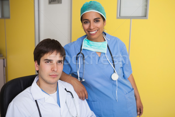 Happy doctor sitting in leather chair with nurse standing in yellow office Stock photo © wavebreak_media