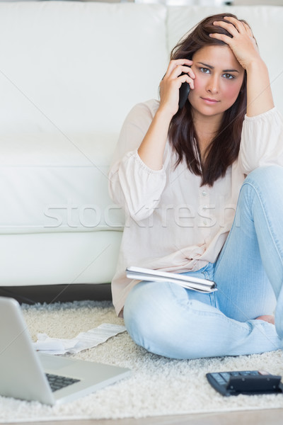 Woman sitting on the carpet in front of bills and calling Stock photo © wavebreak_media
