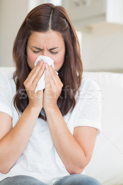 Stock photo: Woman blowing nose on the sofa