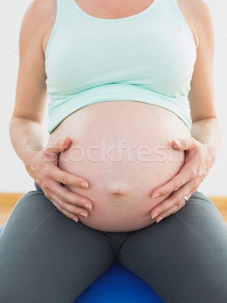 Pregnant woman sitting on blue exercise ball holding her belly Stock photo © wavebreak_media
