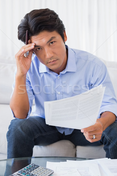Man sitting on couch working out his finances Stock photo © wavebreak_media