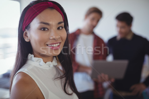 Smiling businesswoman standing with colleagues in background Stock photo © wavebreak_media