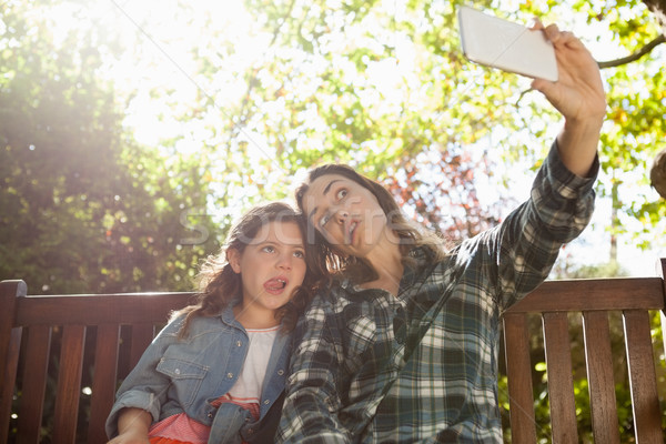Low angle view of woman taking selfie with daughter while making faces against trees Stock photo © wavebreak_media