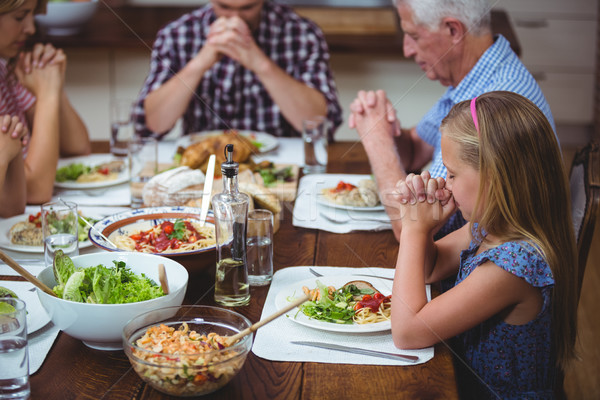 Multi generation family praying with granddad sitting at dining  Stock photo © wavebreak_media