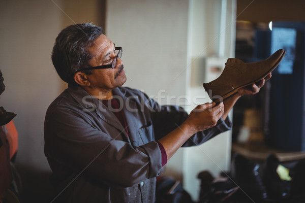 Stock photo: Shoemaker examining a shoe