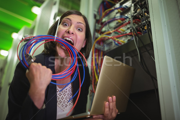 Frustrated technician eating wire and holding laptop Stock photo © wavebreak_media