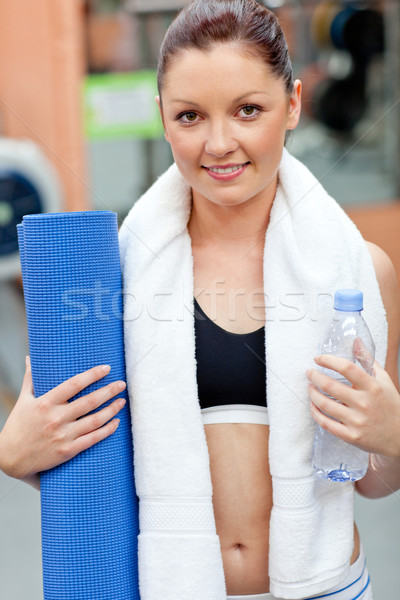 sporty woman holding bottle of water and exercise mat looking at the camera in a fitness centre Stock photo © wavebreak_media
