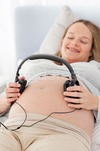 Foto stock: Feliz · mulher · grávida · fones · de · ouvido · barriga · cama · sorrir