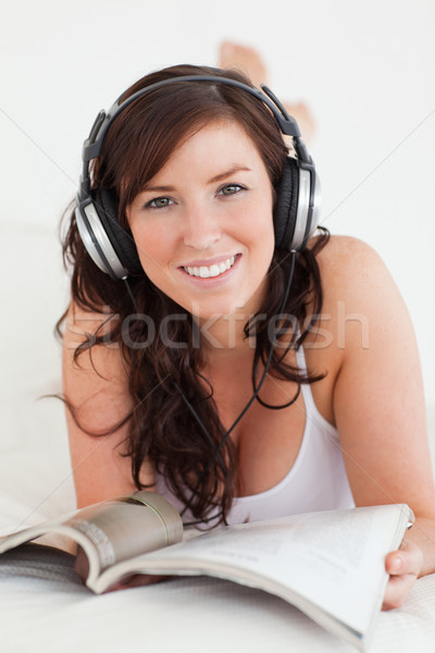 Foto stock: Femenino · auriculares · lectura · revista · cama