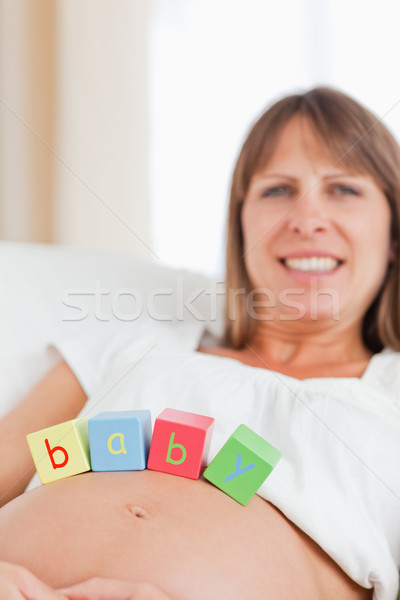 Good looking pregnant woman playing with wooden blocks while lying on a sofa in her living room Stock photo © wavebreak_media