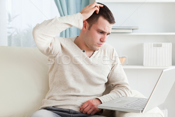 Confused man using a notebook in his living room Stock photo © wavebreak_media