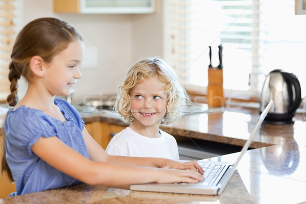 Stock photo: Siblings together on the notebook in the kitchen