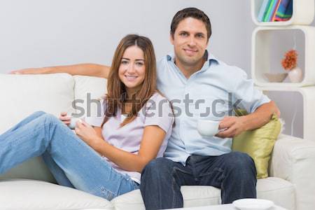 Stock photo: Young couple sitting on the couch and watching television and drinking wine