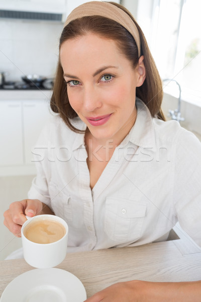 Stock photo: Smiling young woman with coffee cup in kitchen