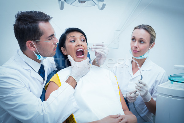 Stock photo: Male dentist with assistant examining womans teeth