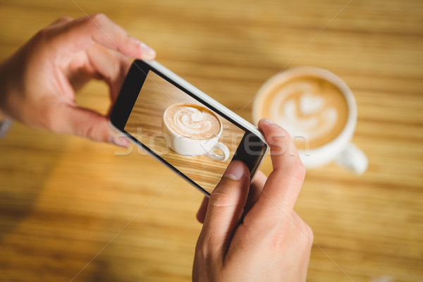 Man photographing his cappuccino with coffee art Stock photo © wavebreak_media
