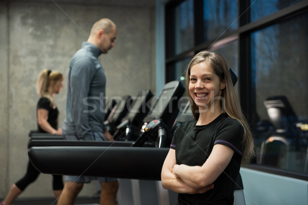 Smiling woman standing with people exercising on treadmill Stock photo © wavebreak_media