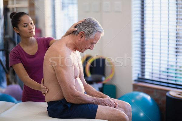 Young female therapist giving back massage to senior male patient sitting on bed Stock photo © wavebreak_media