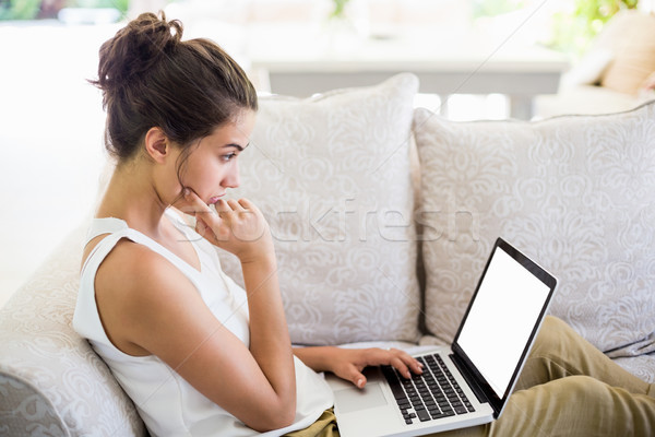 Сток-фото: используя · ноутбук · красивой · сидят · диван · женщину